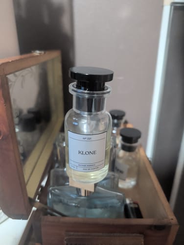 Customer's Klone Scents Collection perfume bottle featuring a clear glass container and black cap inside a wooden box.
