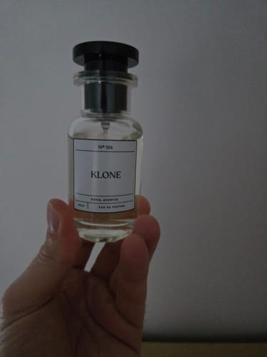 Customer's hand holding a bottle of Klone Scents Collection eau de parfum against a neutral background.