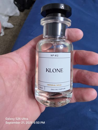 Customer's Imperial Gold fragrance bottle held in hand, showing clear glass bottle and black cap.