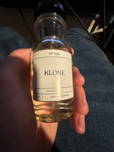 Customer's hand holding a small, clear glass bottle of Klone No 364 Eau de Parfum.