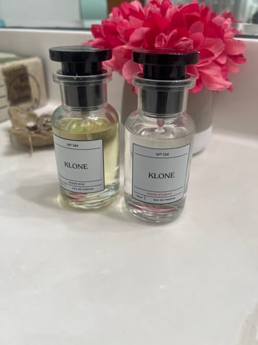 Customer's Rouge Atlantic Klone perfume bottle next to another Klone bottle and pink flowers on a bathroom counter.